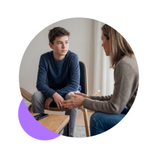 Jugendlicher sitzt am Tisch mit Smartphone und ignoriert Mutter