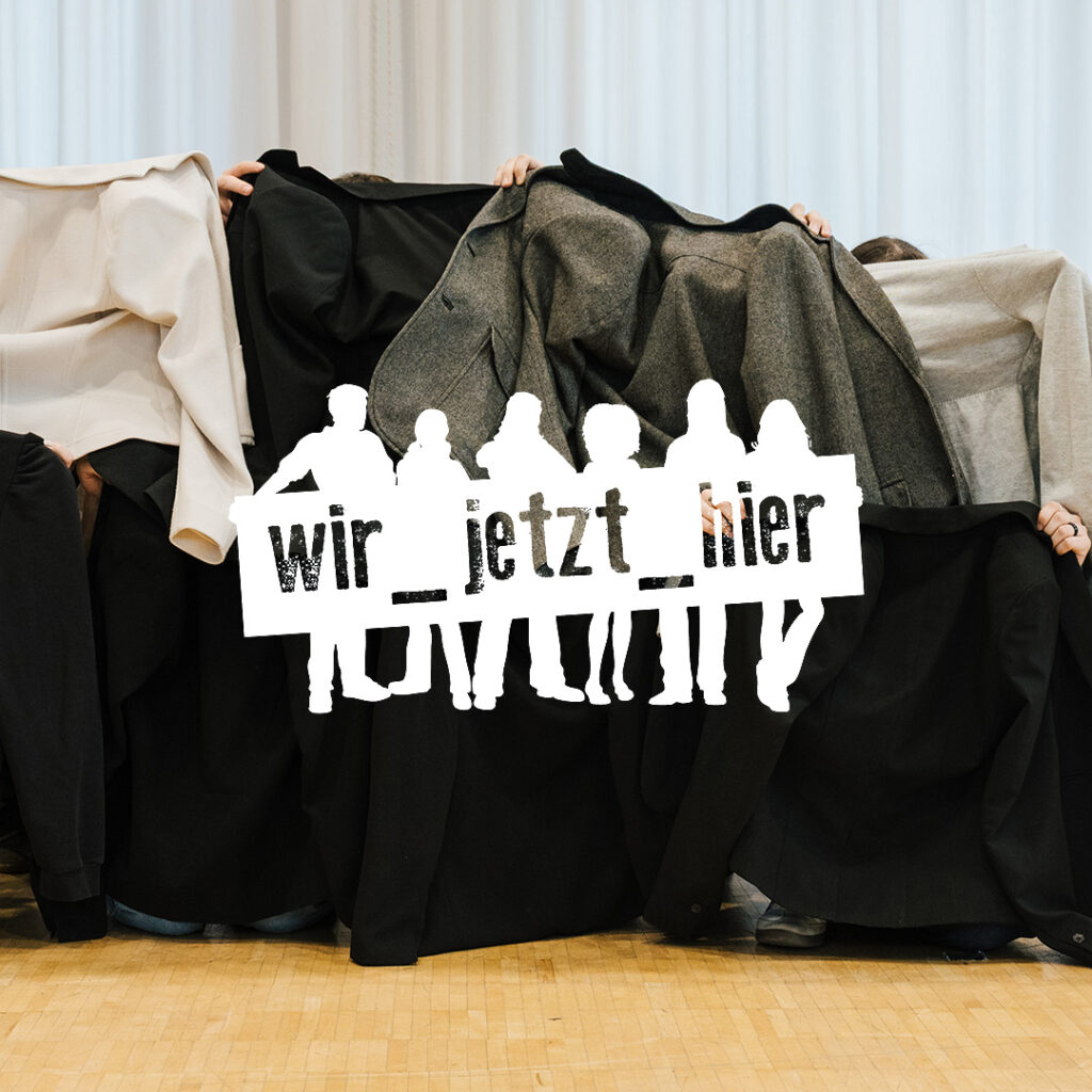 Jugendliche halten Jacken vor sich, Logo der Projektes Wir_Jetzt_hier!
